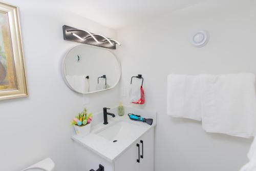 une salle de bain blanche avec un lavabo et un miroir dans l'établissement Cozy Quarters Your Comfy Haven, à Calgary
