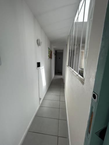 a hallway with white walls and a white tile floor at Etoile d'une Nuit in Bouaye