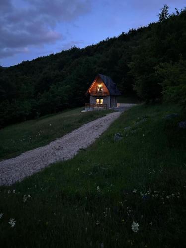 a small cabin in a field with a gravel road at Kuća za odmor LO in Lipovlje
