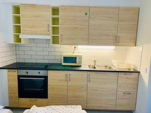 a kitchen with wooden cabinets and a sink and a microwave at Cozy home in nearby Eslöv station in Eslöv
