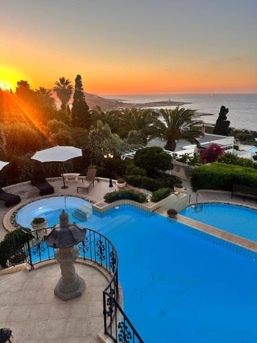 a large swimming pool with a sunset in the background at Madliena Hills Mansion in Is-Swieqi