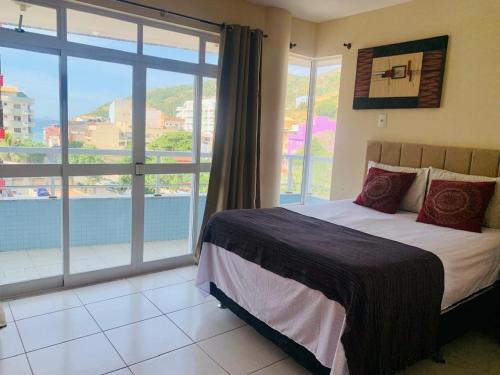 a bedroom with a bed and a large window at Ap prainha top in Arraial do Cabo