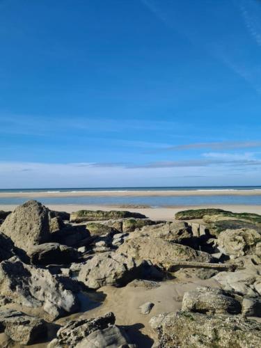 a beach with rocks and the ocean in the background at Mobil-home Vue mer Piscine - Camping La Falaise Equihen-Plage - La Coquille d'Opale in Équihen-Plage