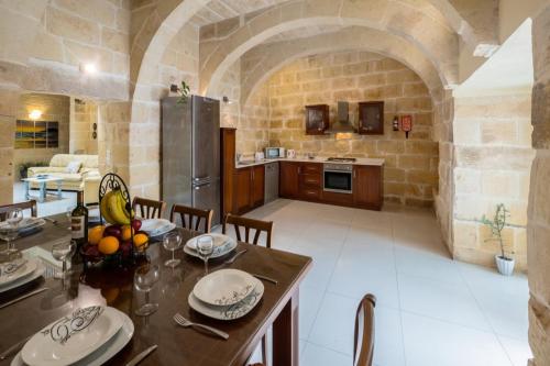 a kitchen and dining room with a table in a stone room at Girgentina Farmhouse in Sannat