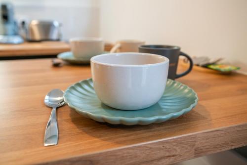 a cup and a plate on a table with a spoon at Le Nid Terracotta Charme et Sérénité à Saint-Brieuc in Saint-Brieuc