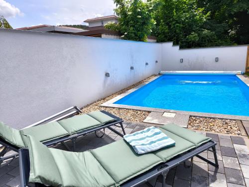 a swimming pool with lounge chairs next to a building at Ferienhaus Isabel mit Pool und Garten Nähe Quedlinburg in Gernrode - Harz