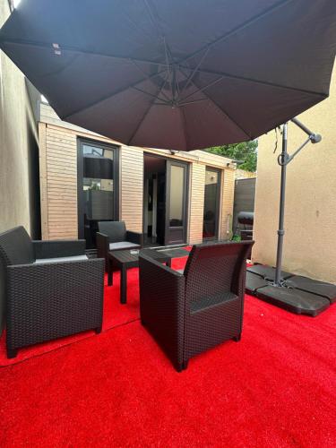 un patio avec deux chaises et un parasol sur un tapis rouge dans l'établissement Cabanon aux films, à Saint-Brieuc
