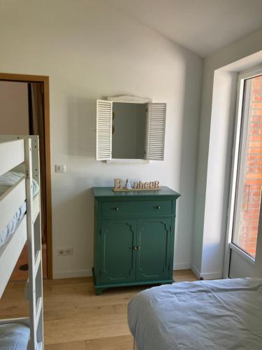 une commode verte dans une chambre avec un miroir dans l'établissement Maison Tamaris proche de l'Océan, à LʼAiguillon-sur-Vie