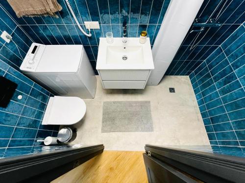 a bathroom with a white sink and blue tiles at Ocean Urban Suite in Palanga