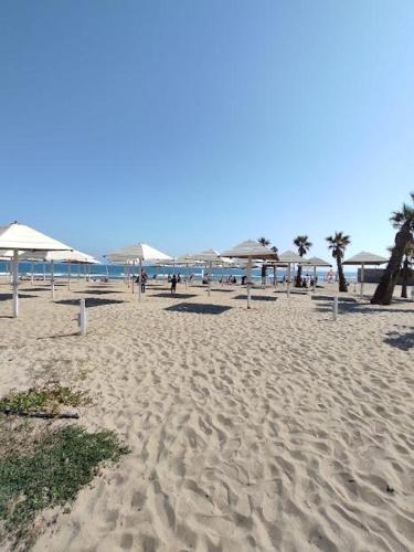 a sandy beach with umbrellas and people on it at Aradas Home in Catania
