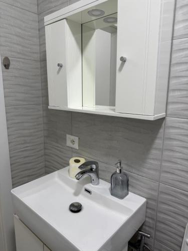 a bathroom with a white sink and a mirror at Rei Apartments in Shëngjin