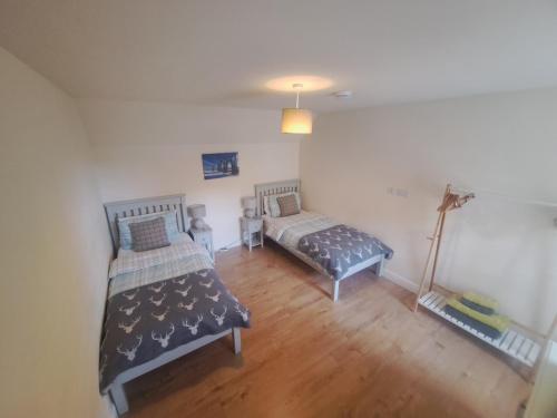 a room with two beds and a lamp in it at Tweed Apartment, Golspie in Golspie