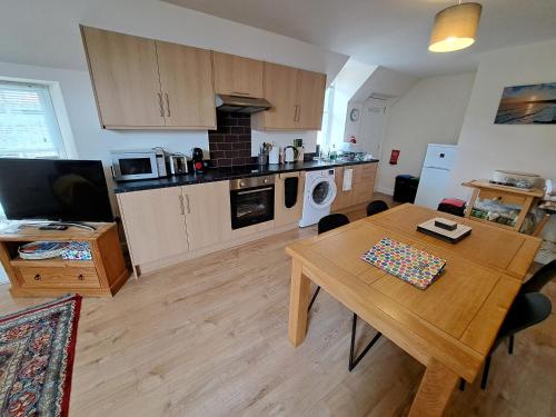 a living room with a table and a kitchen at Tweed Apartment, Golspie in Golspie