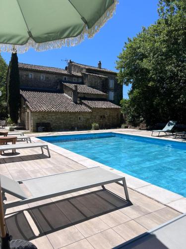 a swimming pool with two chairs and an umbrella at Le Moulin de Montségur in Montségur-sur-Lauzon