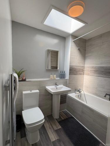 a bathroom with a toilet and a sink and a bath tub at Single bed in mixed shared room in London