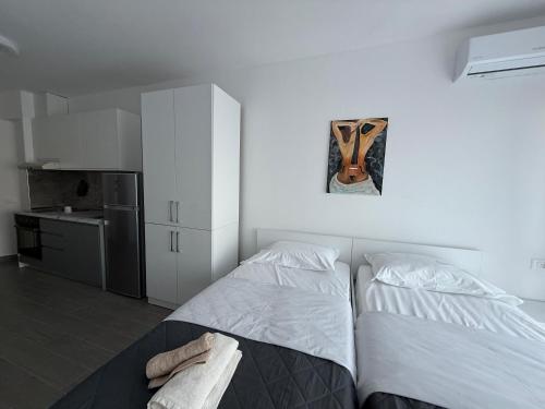 a white bedroom with a bed and a kitchen at Rei Apartment 2 in Lezhë
