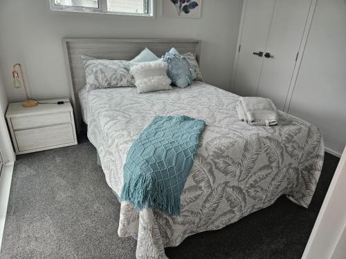 a bedroom with a bed with a comforter and pillows at Modern and Cosy on Seaforth in Bowentown