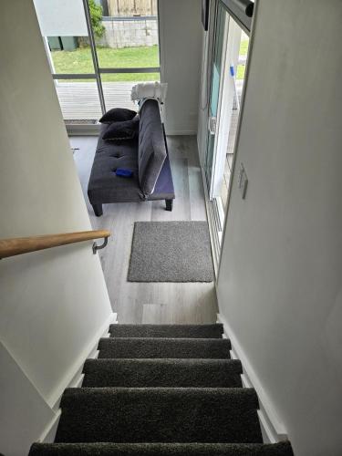 a staircase in a room with a couch and a window at Modern and Cosy on Seaforth in Bowentown