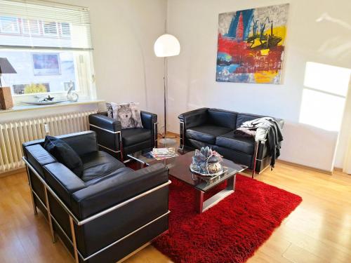 a living room with two couches and a red rug at Chalet an der Bode - Schicke 3 Zi Fewo mit Balkon in Braunlage