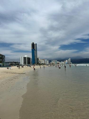 una playa con un montón de gente en el agua en Strand Overnight - 24 Hour check-in - close to major private hospitals - sleeps 1- 4 guests - self catering - quiet neighborhood - week night low rate for single guest - weekends min 2 nights, en Strand