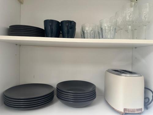 a shelf with plates and cups and a toaster at Le petit Gite de Vendome in Vendôme
