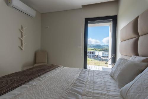a bedroom with a large bed with a large window at Vila Vicente Jacuzzi, Sauna and Parking in São Vicente Ferreira