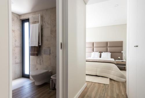 a bedroom with a large bed and a bathroom at Vila Vicente (Jacuzzi, Sauna and Parking) in São Vicente Ferreira