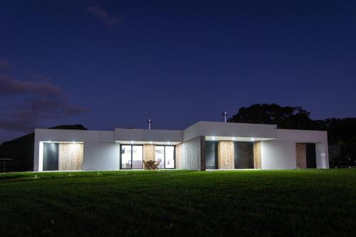 a large white building with a green field at night at Vila Vicente (Jacuzzi, Sauna and Parking) in São Vicente Ferreira