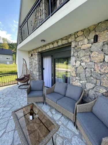 a patio with couches and a table and a stone wall at BOK Holiday VILLAGE Kolasin in Kolašin