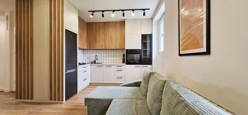 a living room with a couch and a kitchen at Apartament Parkowy in Zamość