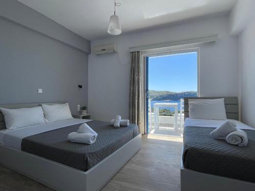 a bedroom with two beds and a large window at Enopia Apartments Himara in Himare