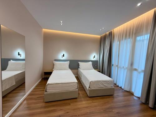 a bedroom with two beds and a large window at Villa24 Vlore in Vlorë