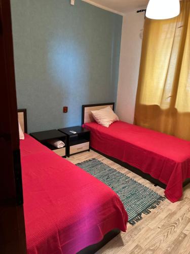 a room with two beds with red sheets and a table at Villa Nikoleta in Sveti Vlas
