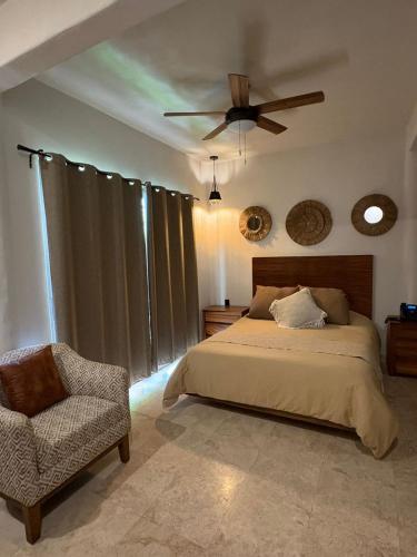 a bedroom with a bed and a ceiling fan and a chair at Villa Marena Hotel Boutique in Coyuca