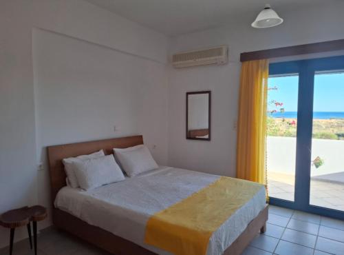 a bedroom with a bed with a view of the ocean at Melissa Apartments in Frangokastello