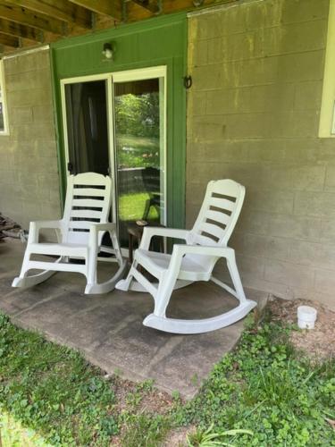 2 chaises blanches assises sur la terrasse couverte d'une maison dans l'établissement Country suite with bath and laundry, à Athens