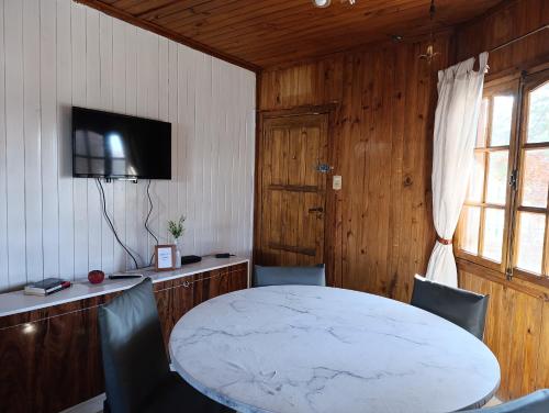 a room with a table and chairs and a television at City Cabin in Uspallata