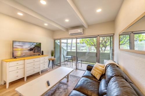 a living room with a couch and a tv at 3mins Walk to Beach! Laundry, Pool, Hot Tub & More in Kihei