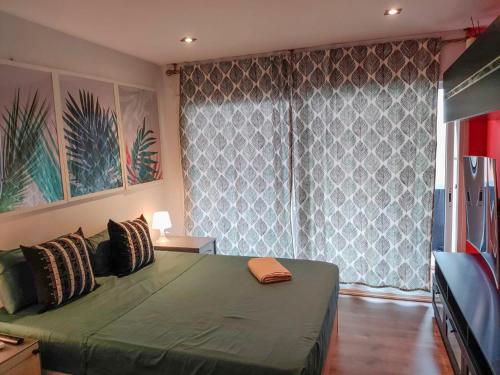 a bedroom with a green bed and a large window at Hab Moderna A 20 Minutos del Centro de Barcelona in Santa Coloma de Gramanet