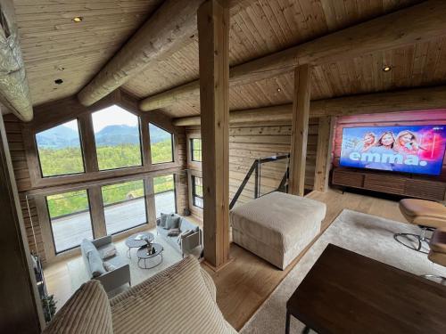 a living room with a large television in a log cabin at Exclusive Fjord Lodge with Private Jacuzzi and Epic Views in Lii