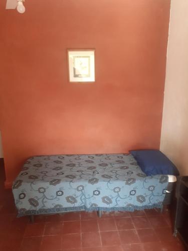 Una cama en una habitación con una pared naranja. en Departamento Monoambiente, en La Rioja