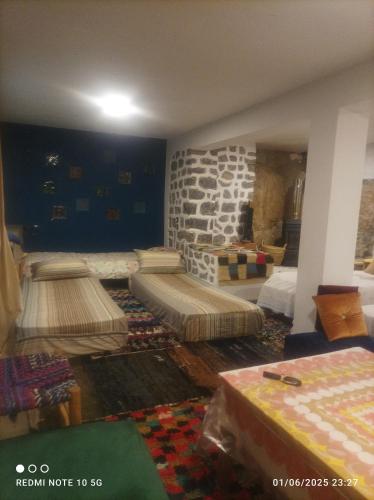 a room with three beds in a room with a fireplace at Refuge AIT M'HAMED in Aït Mehammed