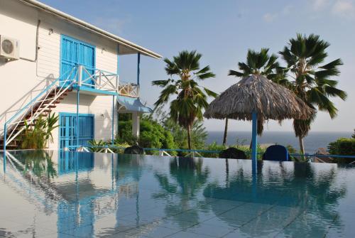 a swimming pool in front of a house with palm trees at Half Moon Blue Hotel in Scarborough