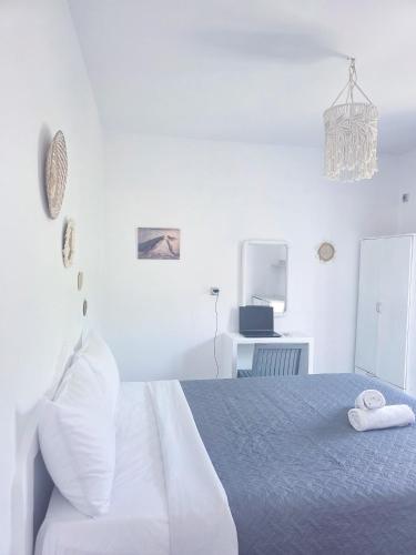 a white bedroom with a bed and a chandelier at Calypso Heaven in Santorini