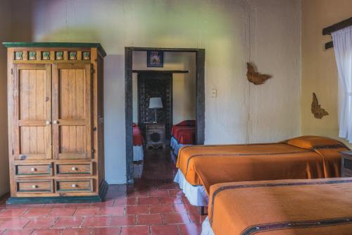 a bedroom with two beds and a dresser and a mirror at Hotel Toliman in San Lucas Tolimán