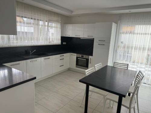 une cuisine avec des armoires blanches et une table et des chaises dans l'établissement La maison du vignoble à BENNWIHR, à Bennwihr