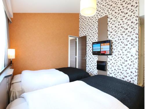 a hotel room with two beds and a flat screen tv at APA Hotel Karuizawa Ekimae Karuizawaso in Karuizawa
