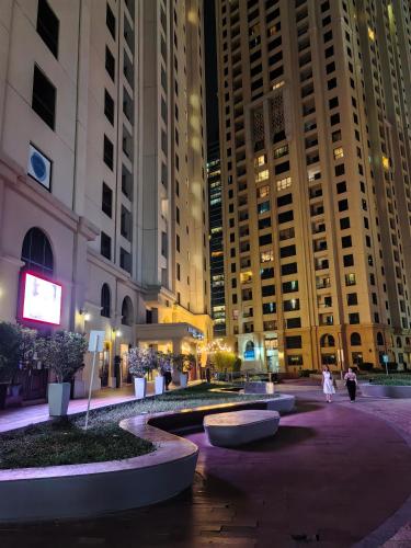 a courtyard in a city at night with tall buildings at Ahlan New Horizon JBR in Dubai