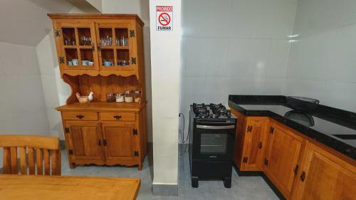 a kitchen with a stove and a wooden cabinet at Hospedagem Caconde Ar condicionado - Wi-fi - Garagem in Caconde