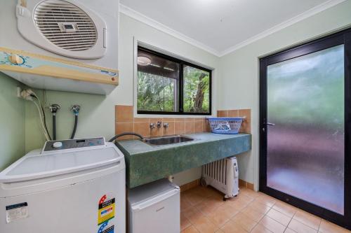 a small kitchen with a sink and a window at Billa Blue by Discover Stradbroke in Point Lookout
